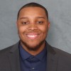 Studio headshot of LaQuan Mack facing the camera against a neutral gray background.